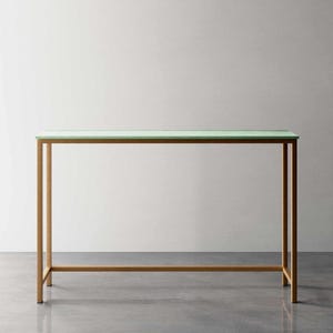 Peut inclure: Une console rectangulaire avec un plateau vert clair et un cadre en métal doré. La table a un design minimaliste et convient à divers styles d'intérieur. Les dimensions de la table sont d'environ 122 cm de long, 36 cm de large et 76 cm de haut.