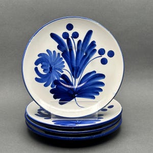 以下が含まれることがあります： 手書き風の「Jane」の文字が入った、黒い持ち手の白いセラミックマグカップ。白い面に置かれています。コーヒーや紅茶に最適です。