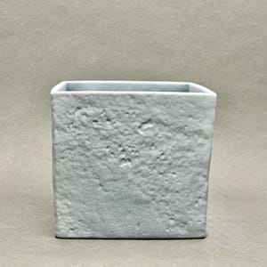May include: A square, pale grey ceramic planter with a textured, stone-like surface. The planter has a smooth, light blue interior and a simple, modern design. Suitable for small plants or decorative use.