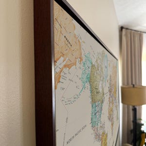 a large world map hanging on a wall, with the countries and regions clearly visible.