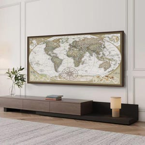 a large world map hanging on a wall above a wooden entertainment center with a lamp on top.