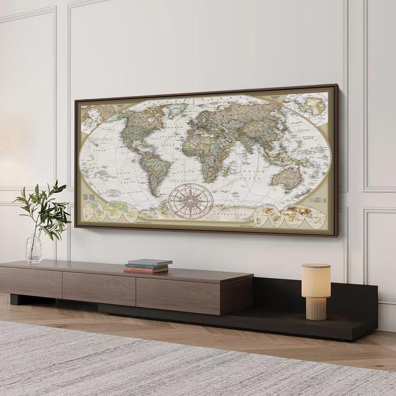 a large world map hanging on a wall above a wooden entertainment center with a lamp on top.