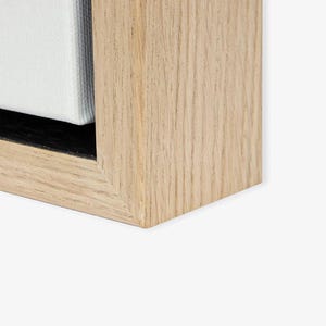 a close-up view of a wooden frame with a light-colored wood grain texture.