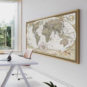 a large world map hanging on a white wall, with a laptop and a chair placed in front of it.