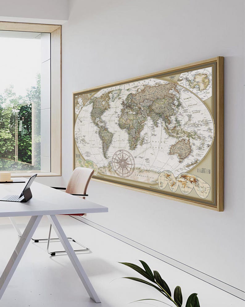 a large world map hanging on a white wall, with a laptop and a chair placed in front of it.