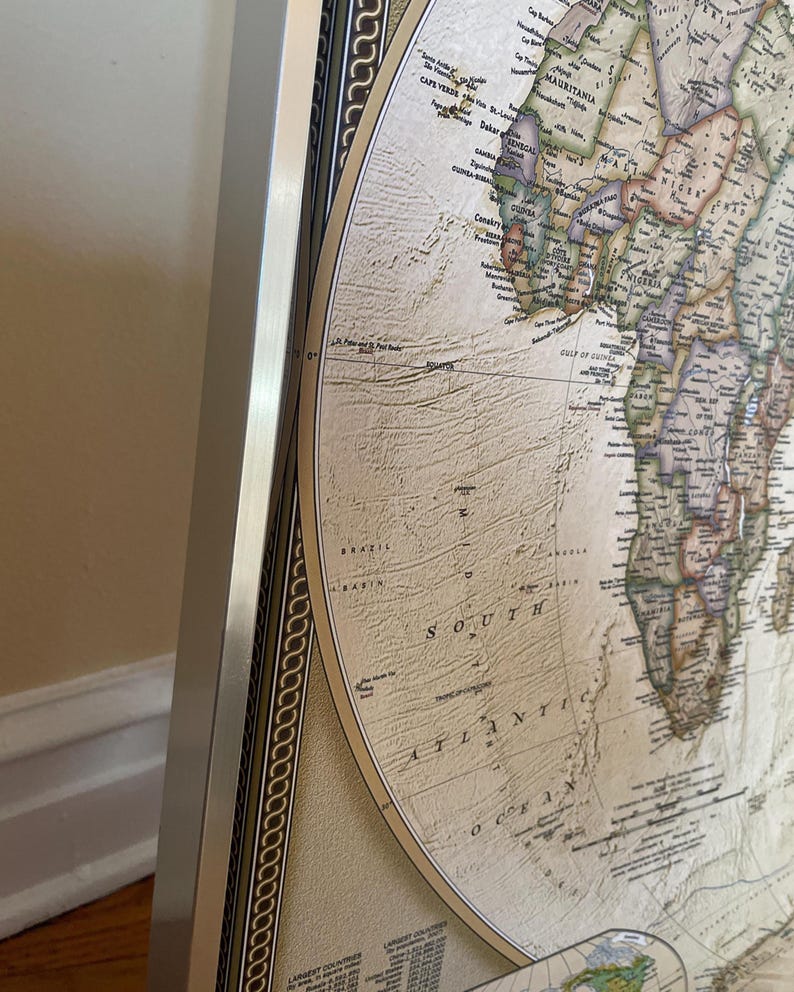 a detailed map of the world, with various countries and regions clearly marked. The map is framed and displayed on a wall, providing a comprehensive view of the world's geography.