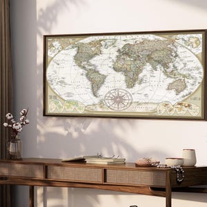 a large world map hanging on a wall above a wooden console table. The table has various items on it, including a vase with flowers, a book, and a pair of glasses.