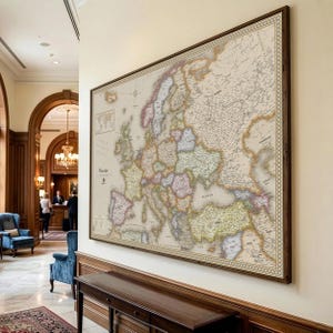 May include: A large framed map of Europe, displayed on a wall. The map features detailed country outlines in various colors, with a brown wooden frame. The map includes the word "Europe".