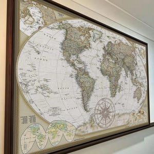 The image is a large, framed world map hanging on a wall.