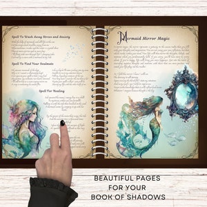 May include: Open book with brown cover and spiral binding. The pages are decorated with watercolor illustrations of mermaids and text. The text includes spells for finding your soulmate, washing away stress and anxiety, and healing. The book is titled "Mermaid Mirror Magic".