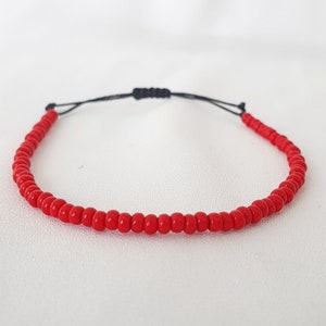 May include: A red beaded bracelet with a black cord.