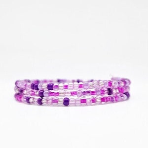 May include: A triple-wrap bracelet made with small purple and clear glass beads.
