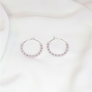 May include: A pair of silver hoop earrings with lavender beads.