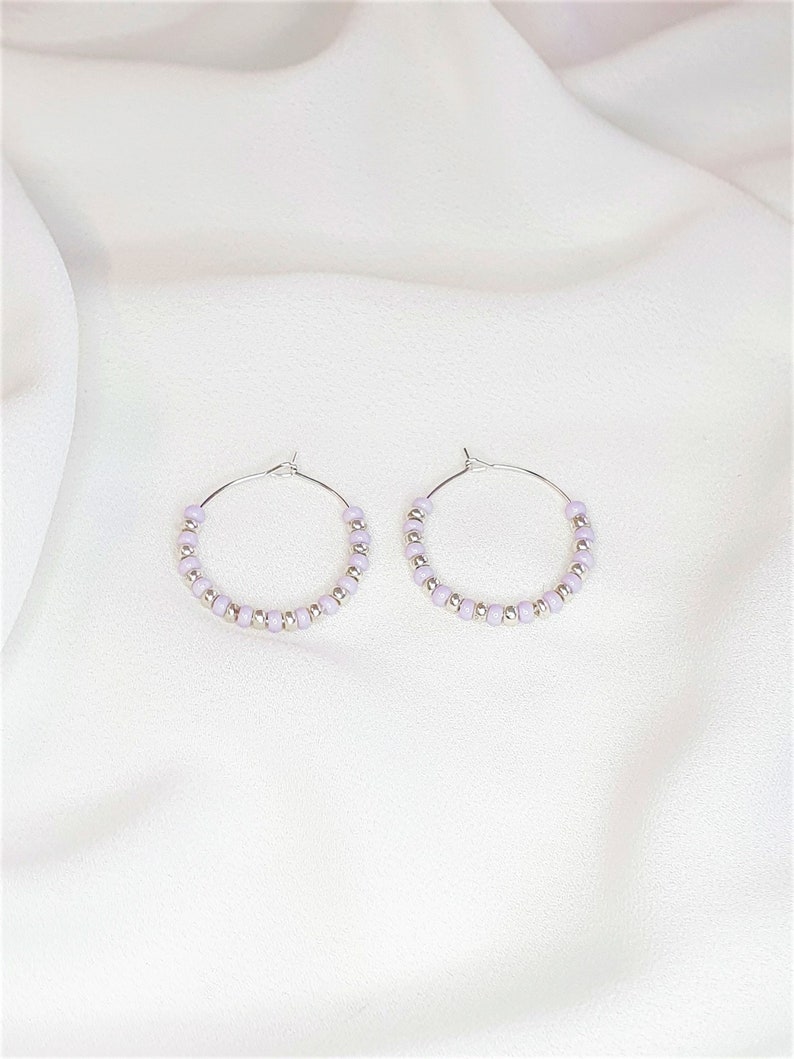 May include: A pair of silver hoop earrings with lavender beads.