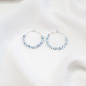 May include: A pair of silver hoop earrings with light blue beads.