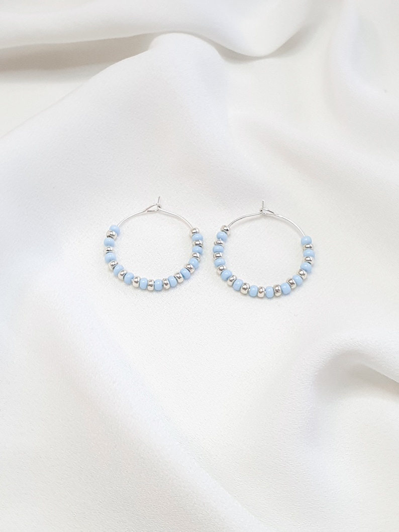 May include: A pair of silver hoop earrings with light blue beads.