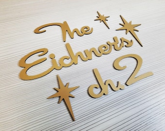 May include: Gold wooden cutout letters spelling "The Eichnerts Ch 2" with two gold star cutouts.