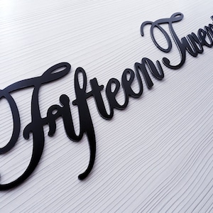 May include: Black metal sign with the words "Fifteen Twenty" in a cursive font.