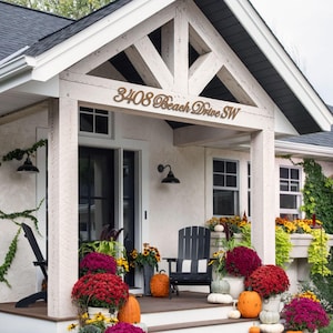May include: A house exterior with a porch decorated for fall. The porch features a black chair, pumpkins, and colorful mums. The address "3408 Beach Drive SW" is displayed above the door.