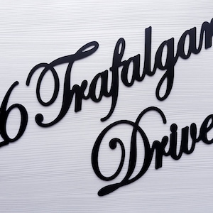 May include: Black wooden house number sign with the number 16 and the words "Trafalgar Drive" in a cursive font.