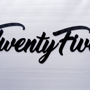 May include: Black acrylic cutout of the word "Twenty Five" in a cursive font.