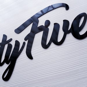 May include: Black and white sign with the word "Twenty Five" written in a stylized script font.