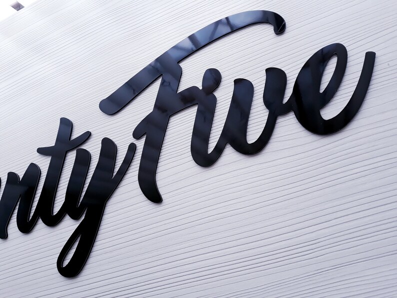 May include: Black and white sign with the word "Twenty Five" written in a stylized script font.