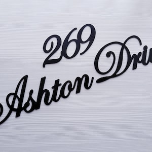 May include: Black cursive lettering on a white background reads "269 Ashton Drive".