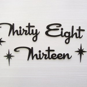 May include: Black paper cutouts of the words "Thirty Eight" and "Thirteen" with three black star shapes.