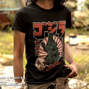 May include: Black t-shirt featuring a vintage-style graphic of Godzilla, a giant monster, with the Japanese text "Gojira" and "Embu-O" in red. The graphic also includes a rising sun and the text "Never-ending Nuclear Nightmare".