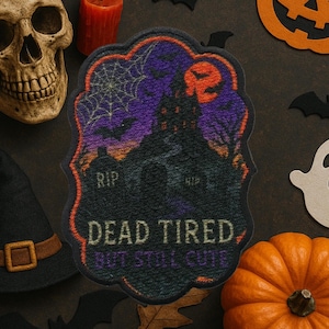 May include: A Halloween-themed decorative mat with a haunted house design, bats, and a full moon. The mat has the text "DEAD TIRED BUT STILL CUTE" and is surrounded by a skull, a witch's hat, a pumpkin, and other Halloween decorations.
