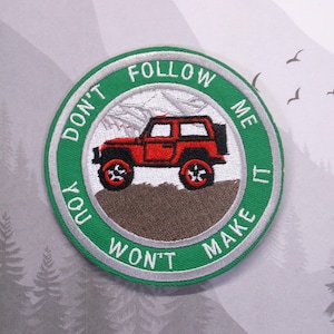 以下が含まれることがあります： 赤いジープと「Don't Follow Me You Won't Make It」というテキストが書かれた緑と白の刺繍パッチ。