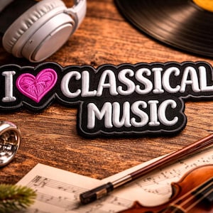 May include: A patch with the text "I ❤️ CLASSICAL MUSIC" and a pink heart, surrounded by musical instruments including a violin, trumpet, headphones, and a vinyl record on a wooden surface. The patch has a black background with white embroidered letters.