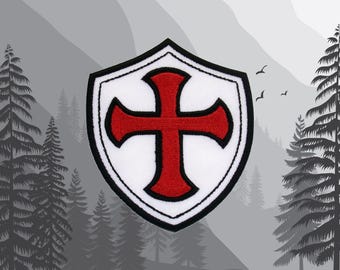 Peut inclure: Un bouclier blanc avec une croix rouge au centre. Le bouclier a un contour noir et est brodé.