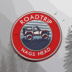 May include: Red and white embroidered patch with a jeep silhouette and the text "ROADTRIP NAGS HEAD" in a circle.