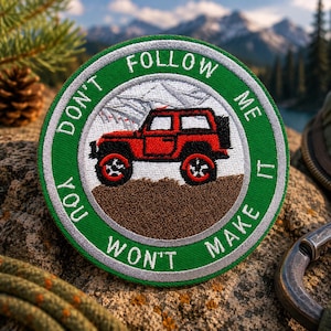 May include: Embroidered patch featuring a red off-road vehicle. The patch has a green border with the text "DON'T FOLLOW ME IT YOU WON'T MAKE IT" in white. The background depicts a mountain landscape.