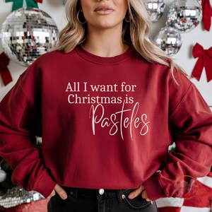 May include: Red Christmas sweatshirt with the text "All I want for Christmas is Pasteles" in white.