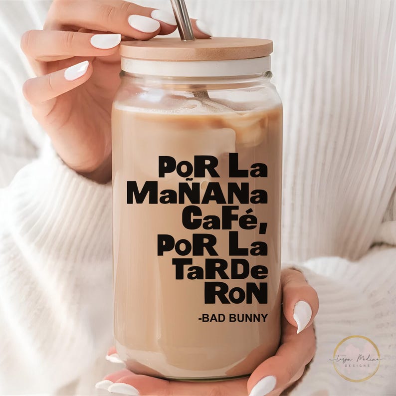 May include: A clear glass tumbler with a wooden lid and a black and white graphic that reads "Por La Ma&ntilde;ana Caf&eacute;, Por La Tarde Ron - Bad Bunny".