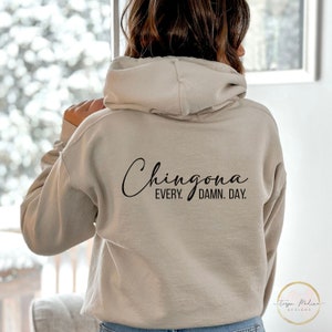May include: A beige hoodie with the text "Chingona Every. Damn. Day." printed on the back.