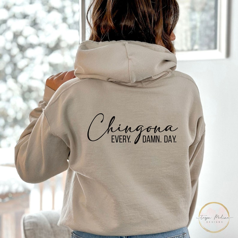 May include: A beige hoodie with the text "Chingona Every. Damn. Day." printed on the back.