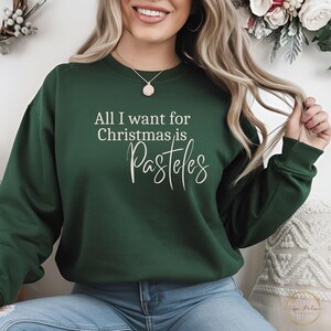 May include: A green sweatshirt with the text "All I want for Christmas is Pasteles" in white lettering.