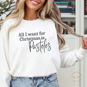 May include: White sweatshirt with the text "All I want for Christmas is Pasteles" printed on the front.