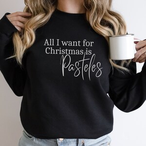 May include: Black sweatshirt with white text that reads "All I want for Christmas is Pasteles".