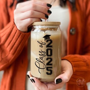 May include: A clear glass mason jar with a wooden lid filled with iced coffee. The jar has a black vinyl decal that says "Class of 2022" with a graduation cap above the 2.