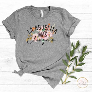 May include: Gray t-shirt with a floral design and the text "La Abuelita Mas Chingona" printed on the front.