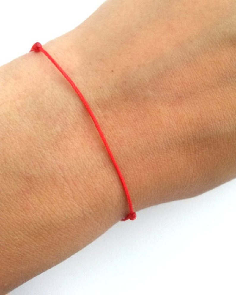 May include: A simple red string bracelet tied in a knot.