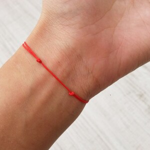 May include: A red string bracelet tied around a wrist.