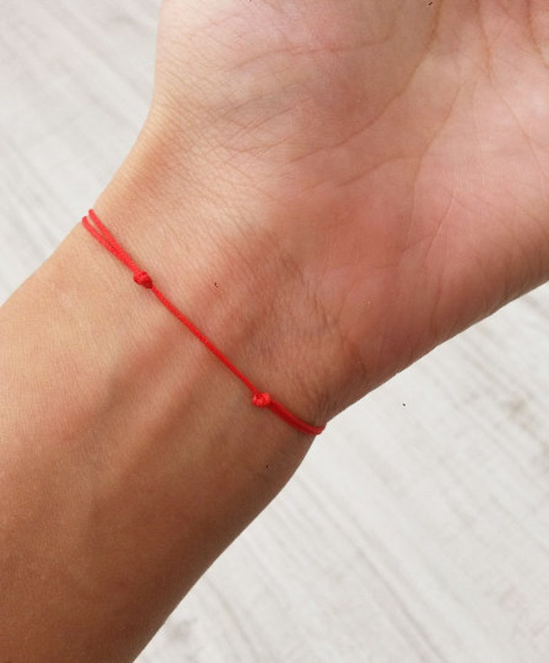 May include: A red string bracelet tied around a wrist.