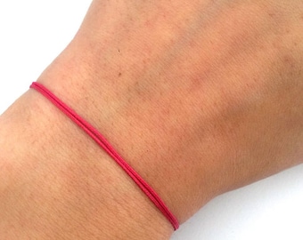 Puede incluir: Una pulsera simple de cuerda roja en la muñeca de una persona.
