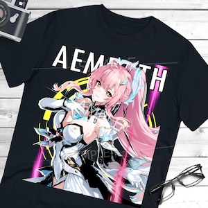 Może przedstawiać: Czarny t-shirt z kolorową ilustracją w stylu anime przedstawiającą postać żeńską z różowymi włosami i białym strojem. Tekst "AEMPATH" jest wydrukowany na górze na biało.